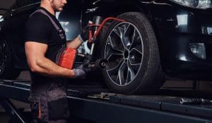 homem musculoso esta consertando a roda do carro com ferramenta especial no auto servico 613910 3825